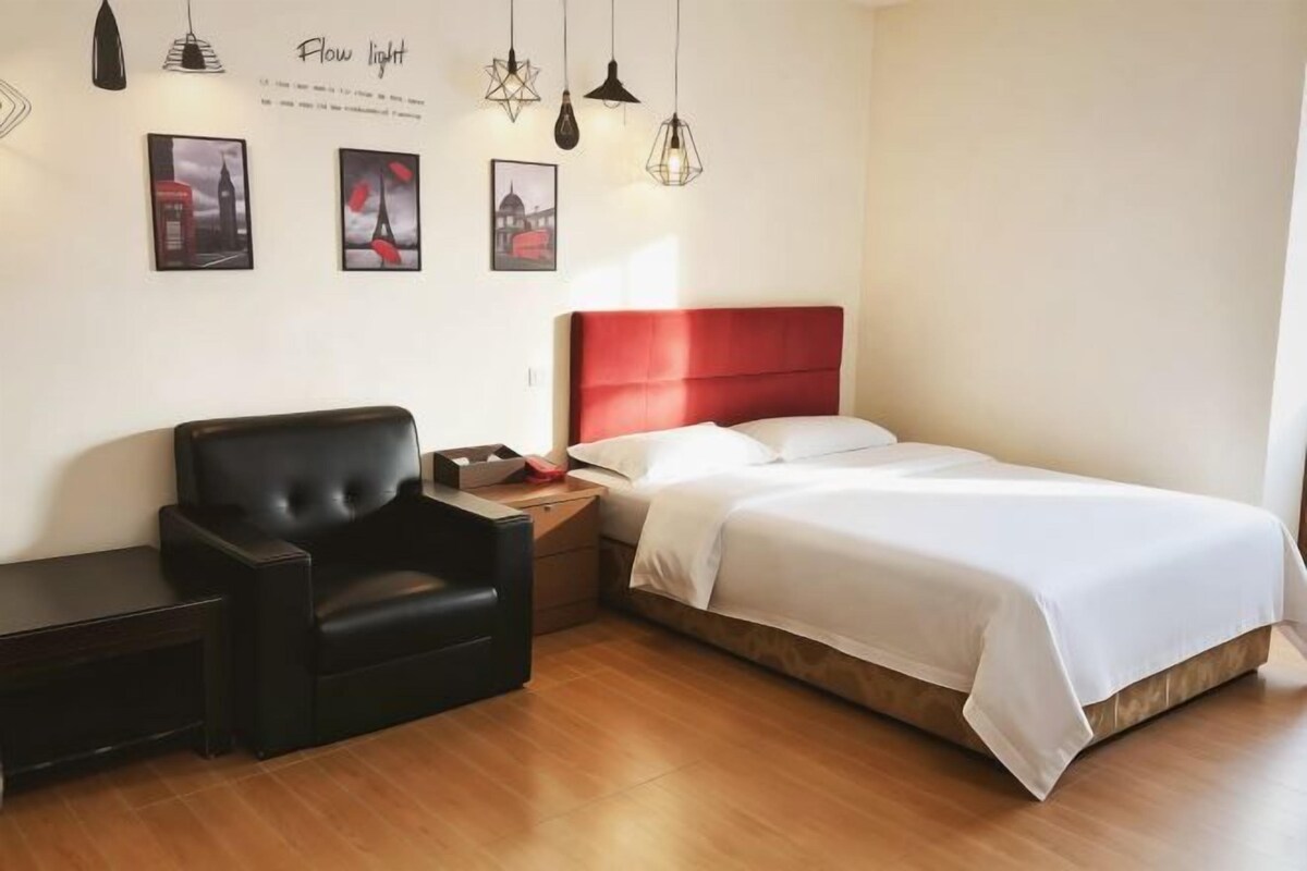 Habitación de hotel con cama, una silla, una mesita de noche y decoración en la pared.