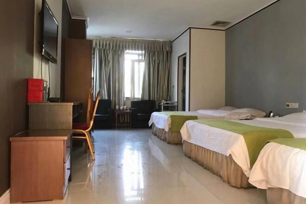 A hotel room with a bed, a desk, a chair, a TV, and a window with curtains.