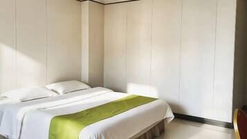 Un dormitorio con cama, un plaid verde y paredes blancas.