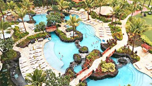 Un resort con varias piscinas, palmeras y zonas de descanso.