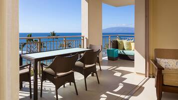 A balcony with a table and chairs, a sofa, and a view of the ocean.
