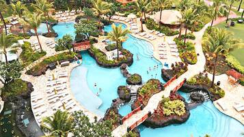 A resort with multiple swimming pools, palm trees, and lounge areas.