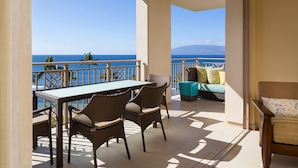 A balcony with a table and chairs, a sofa, and a view of the ocean.