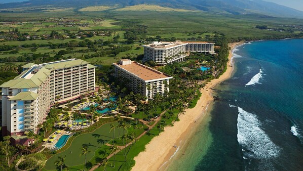 A resort with multiple buildings, a beach, and a pool area.