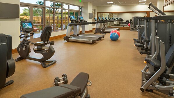 A gym with cardio equipment, weight machines, and a bench.