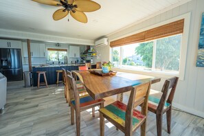 A spacious kitchen with white cabinets, a wooden dining table, and colorful chairs.