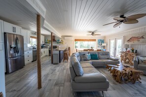 A spacious kitchen with modern appliances, a dining area with a large table, and a cozy seating area with a sectional sofa and a wooden coffee table.