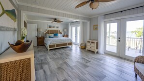 Une chambre spacieuse avec un grand lit, des ventilateurs de plafond et une vue sur l’extérieur.