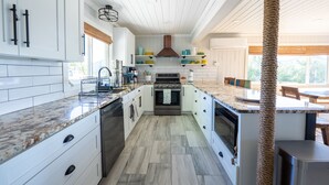 Une cuisine moderne avec des meubles blancs, un îlot central et un porte-ustensiles suspendu.