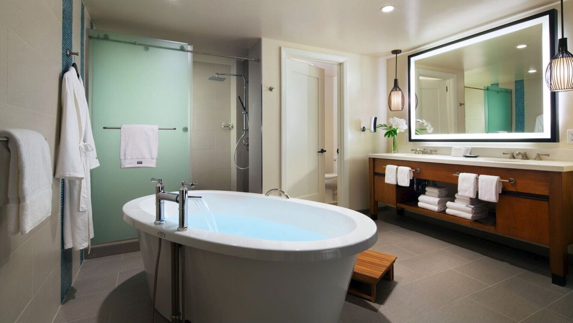 A modern bathroom with a freestanding bathtub, a walk-in shower, and a vanity with a large mirror.