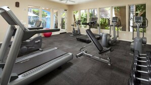 A gym with treadmills, weight machines, and dumbbells.