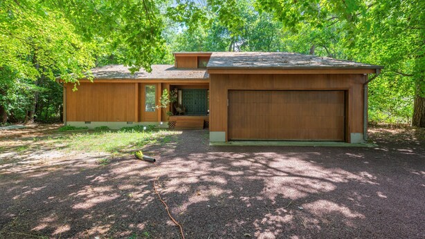 A two-story wooden house with a garage, surrounded by dense green trees. - Spacious Home to Create Memories - access to Bay river and beaches (Millsboro)