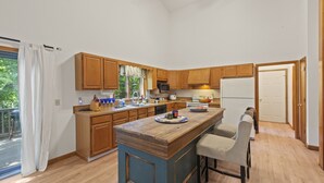 A spacious kitchen with wooden cabinets, a central island, and a dining area with bar stools. - Spacious Home to Create Memories - access to Bay river and beaches (Millsboro)