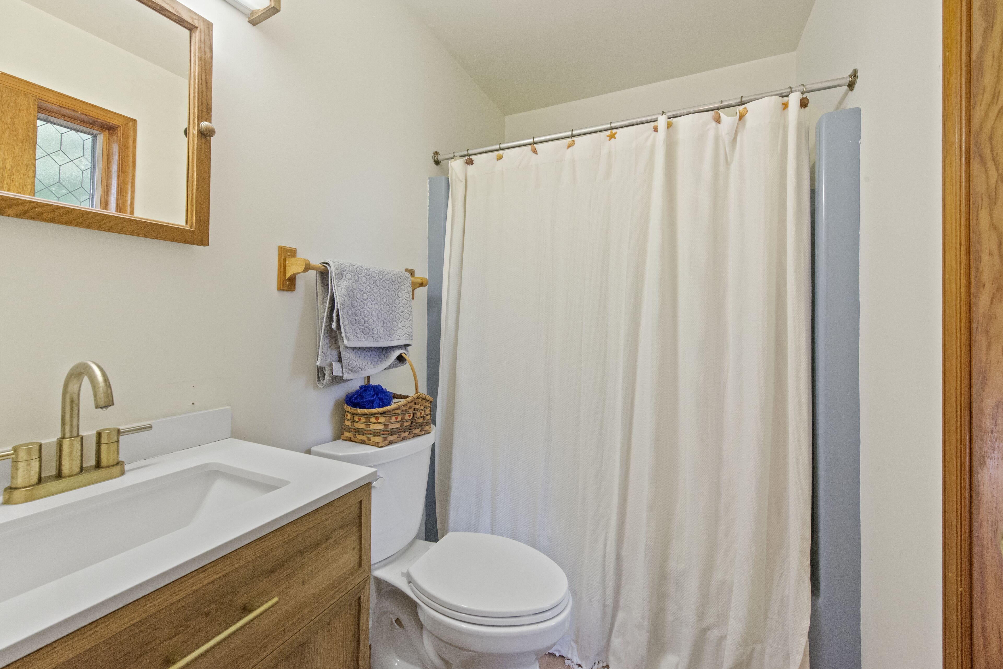 A bathroom with a white sink, a wooden vanity, a white toilet, and a shower curtain.