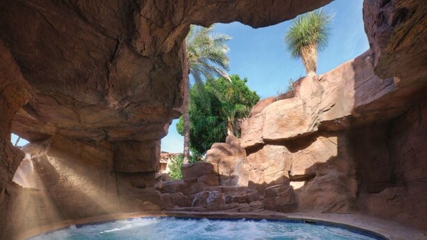 A hot spring pool with a waterfall, surrounded by rocky formations and palm trees. - 1 Bedroom - Sheraton Desert Oasis - Full Resort Access (Scottsdale)