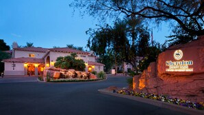 A hotel entrance with a sign reading "Sheraton Desert Oasis".