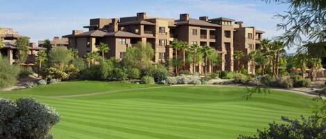 A multi-story hotel with a landscaped lawn and palm trees.