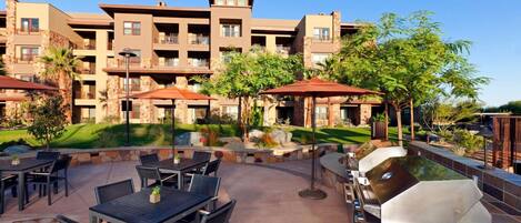 Un resort con comedor al aire libre, zonas de barbacoa, edificios de piedra y piscina.