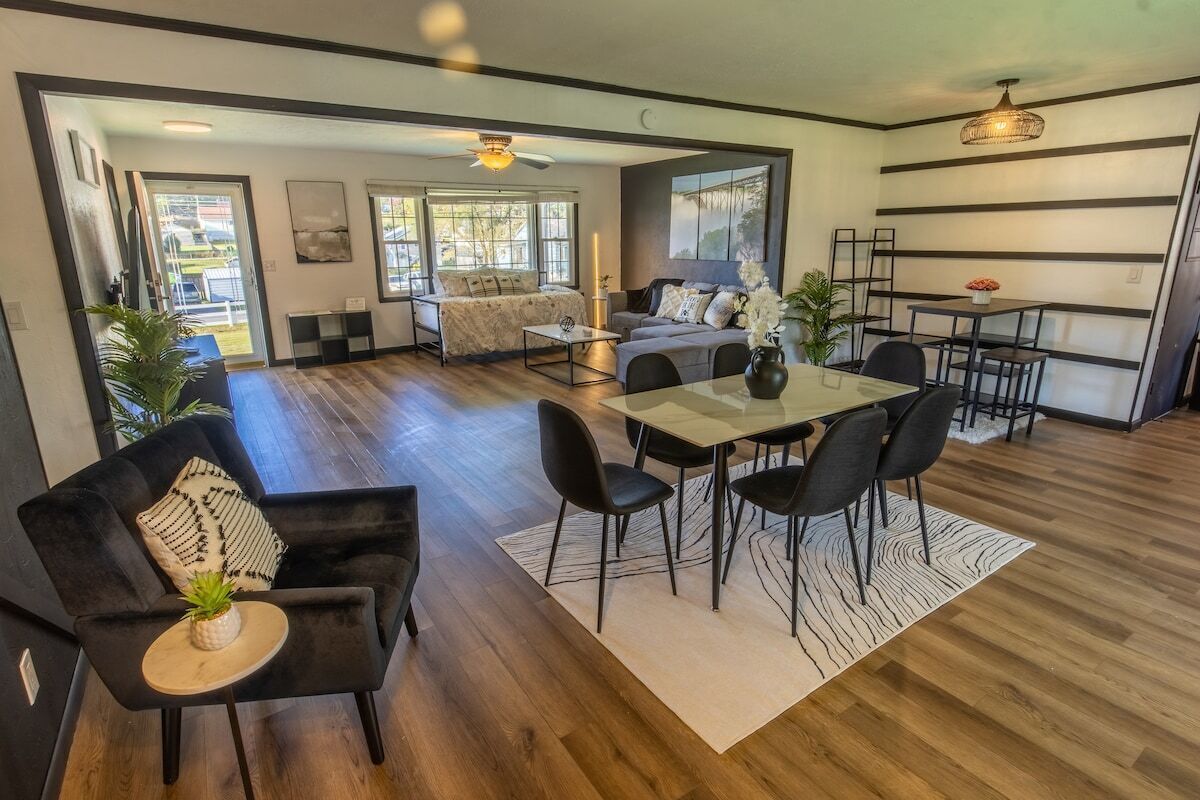 Un salon moderne comprenant un coin repas, un plancher en bois et une grande fenêtre laissant entrer la lumière naturelle.