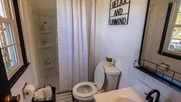 Une salle de bain équipée de toilettes, d’un rideau de douche, d’un lavabo et d’un porte-serviettes.
