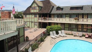 Um hotel com piscina, varandas e área de estar ao ar livre.