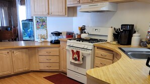 A kitchen with wooden cabinets, a stove, a sink, and various appliances.