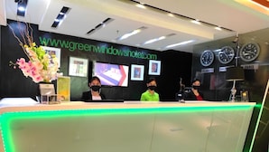 A hotel reception desk with a green LED light strip, a website sign, framed pictures, and clocks displaying different cities.