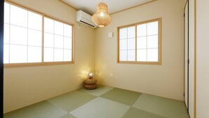 A room with tatami mat flooring, a traditional woven light fixture, and sliding doors. - Condomium Motobu Sakura Terrace (Motobu)