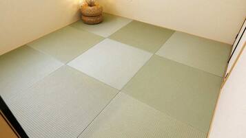 A tatami mat room with a woven basket and a wall-mounted light fixture.