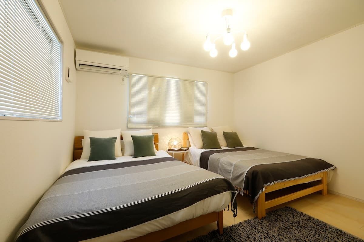 A bedroom with two single beds, a bedside table with a lamp, and a ceiling light fixture.