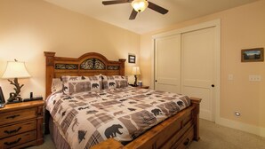 Ein Schlafzimmer mit einem hölzernen Bett, zwei Nachttischen mit Lampen, einem Deckenventilator und einer weißen Tür.