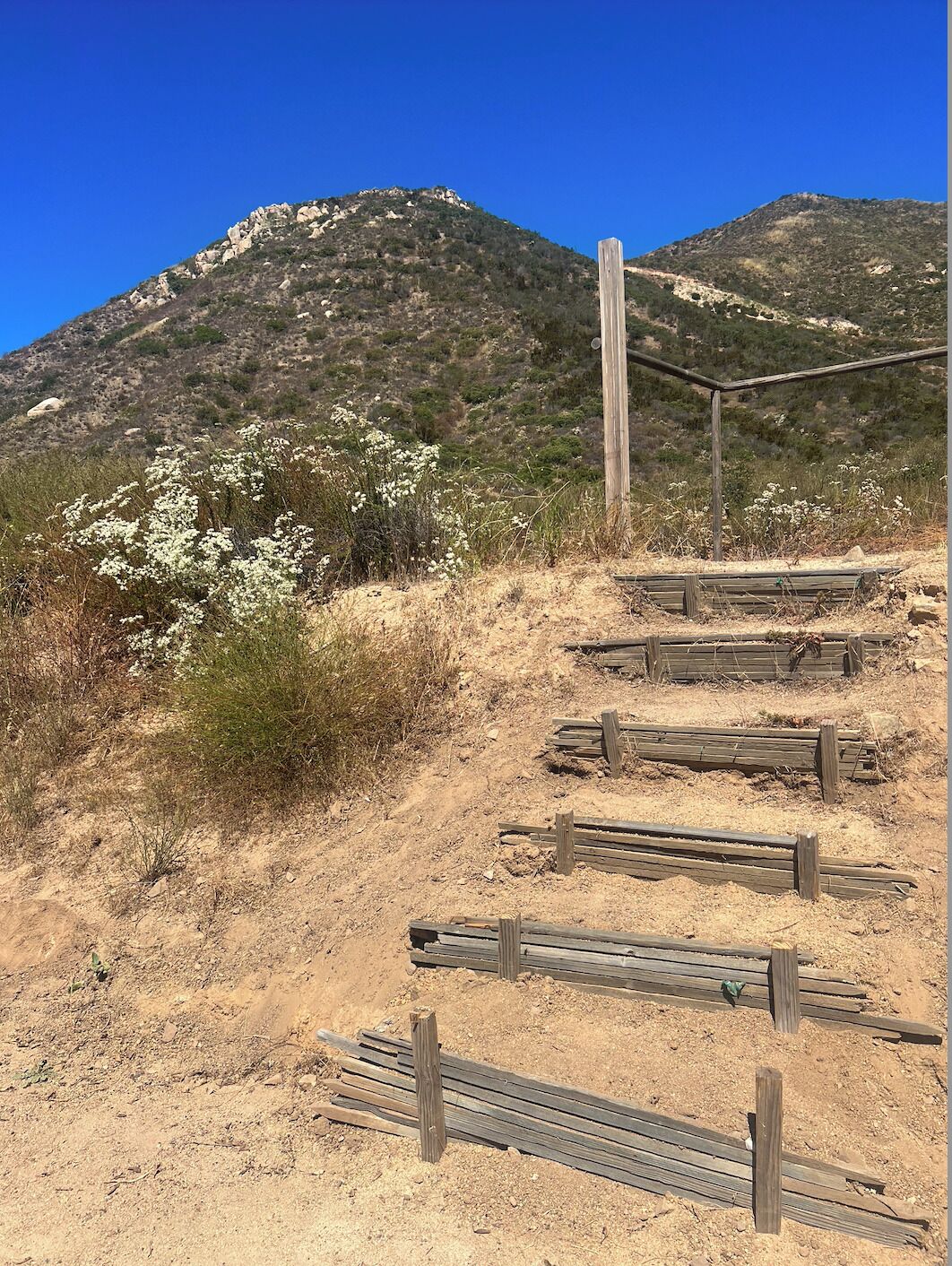 A desert landscape with a wooden structure and a dirt path leading up a hill.