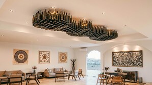 A spacious living room with a high ceiling, a chandelier, and a large painting. -  Villa Montefiori (Valle de Guadalupe)
