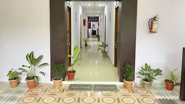 A hotel lobby with a reception desk, a fire extinguisher, and potted plants. - Purnima Resort Neil Island (Port Blair)