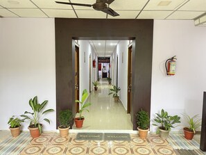 A hotel lobby with a reception desk, a fire extinguisher, and potted plants. - Purnima Resort Neil Island (Port Blair)