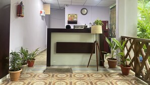 A reception area with a reception desk, a clock, a fire extinguisher, and potted plants. - Purnima Resort Neil Island (Port Blair)