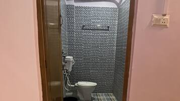 Une petite salle de bain comprenant des toilettes, une douche et un mur décoré d’un motif.