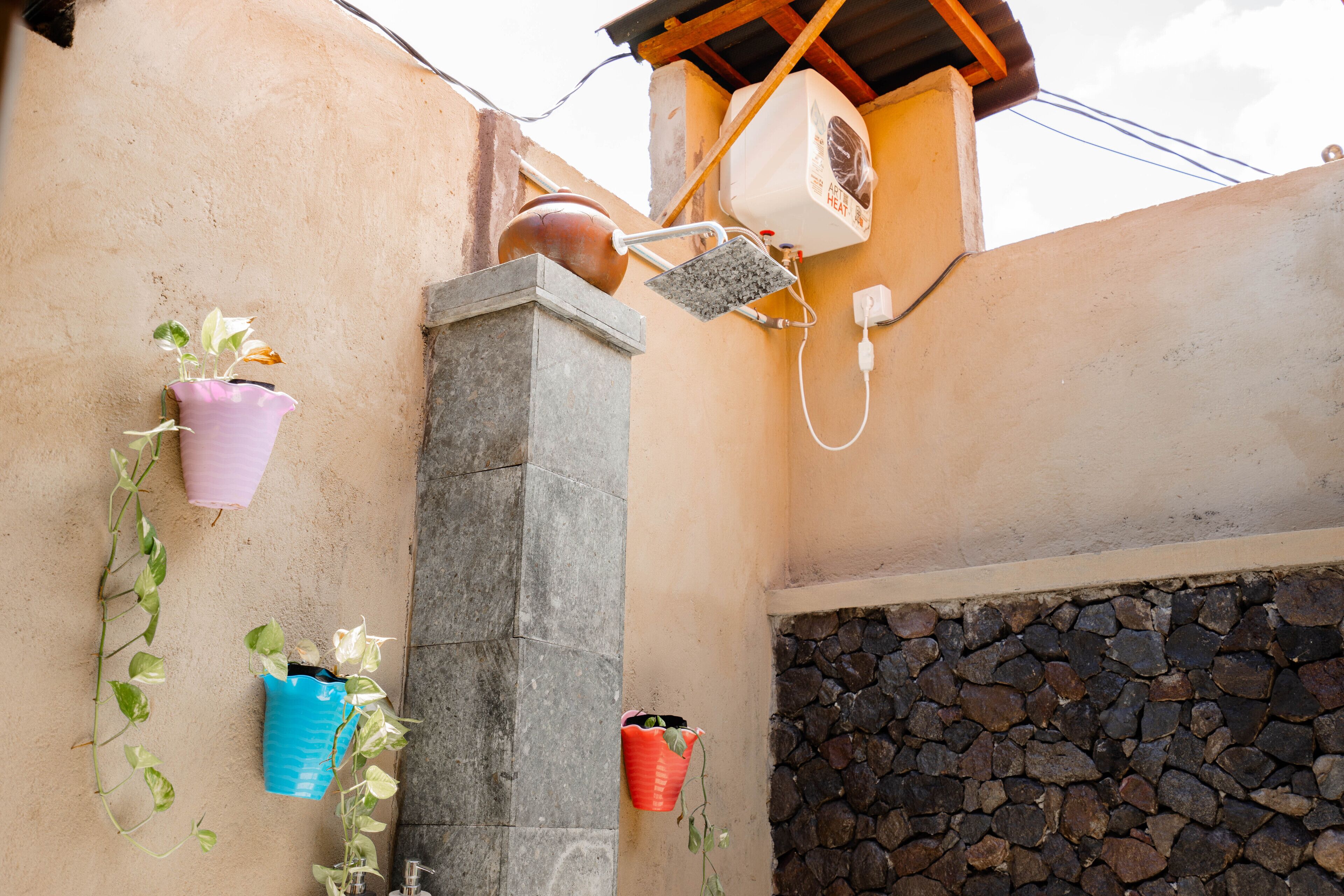 Pared con macetas, pared de piedra y fuente de agua.