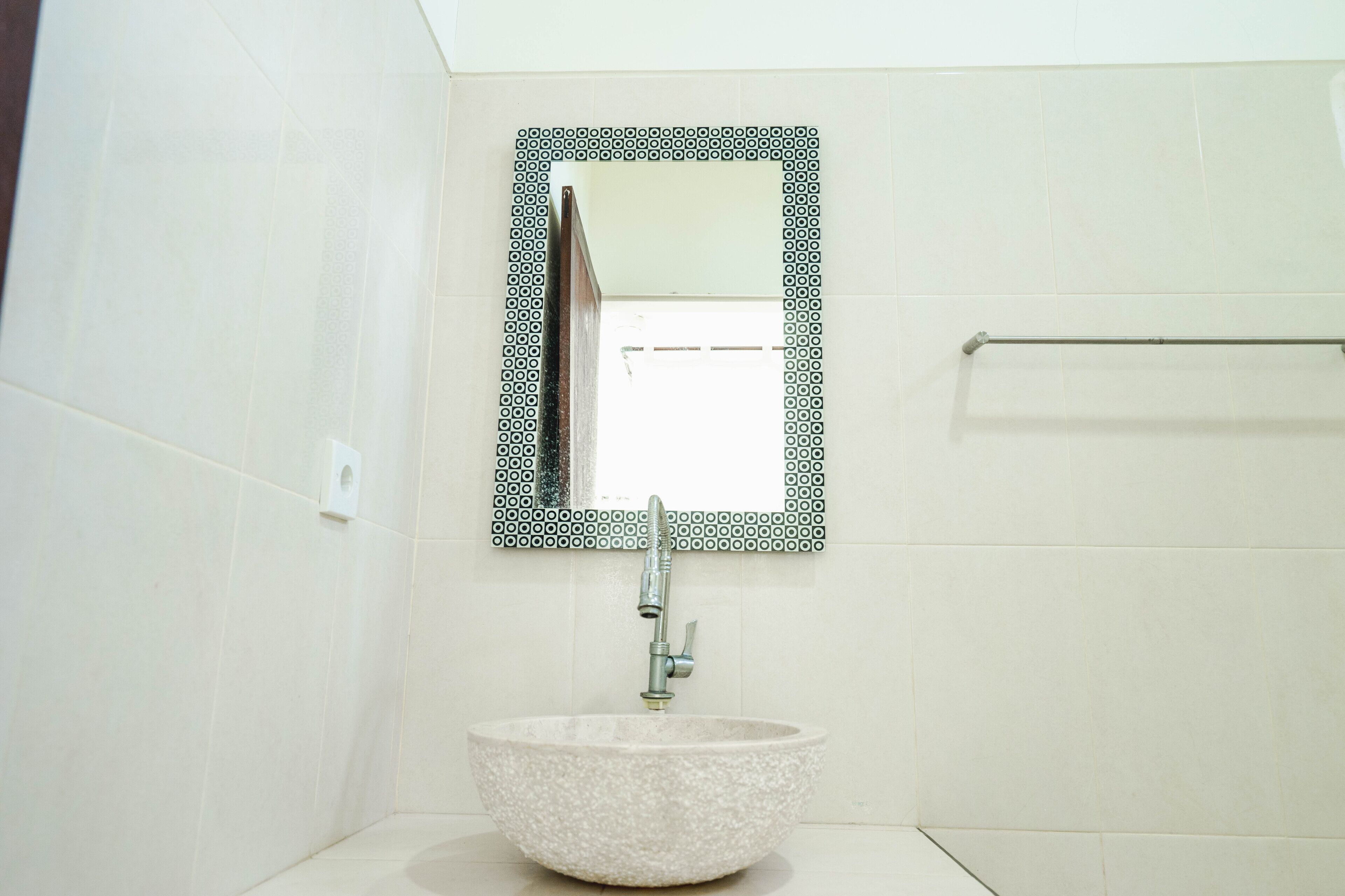 A bathroom with a white sink, a mirror with a black frame, and a towel rack.