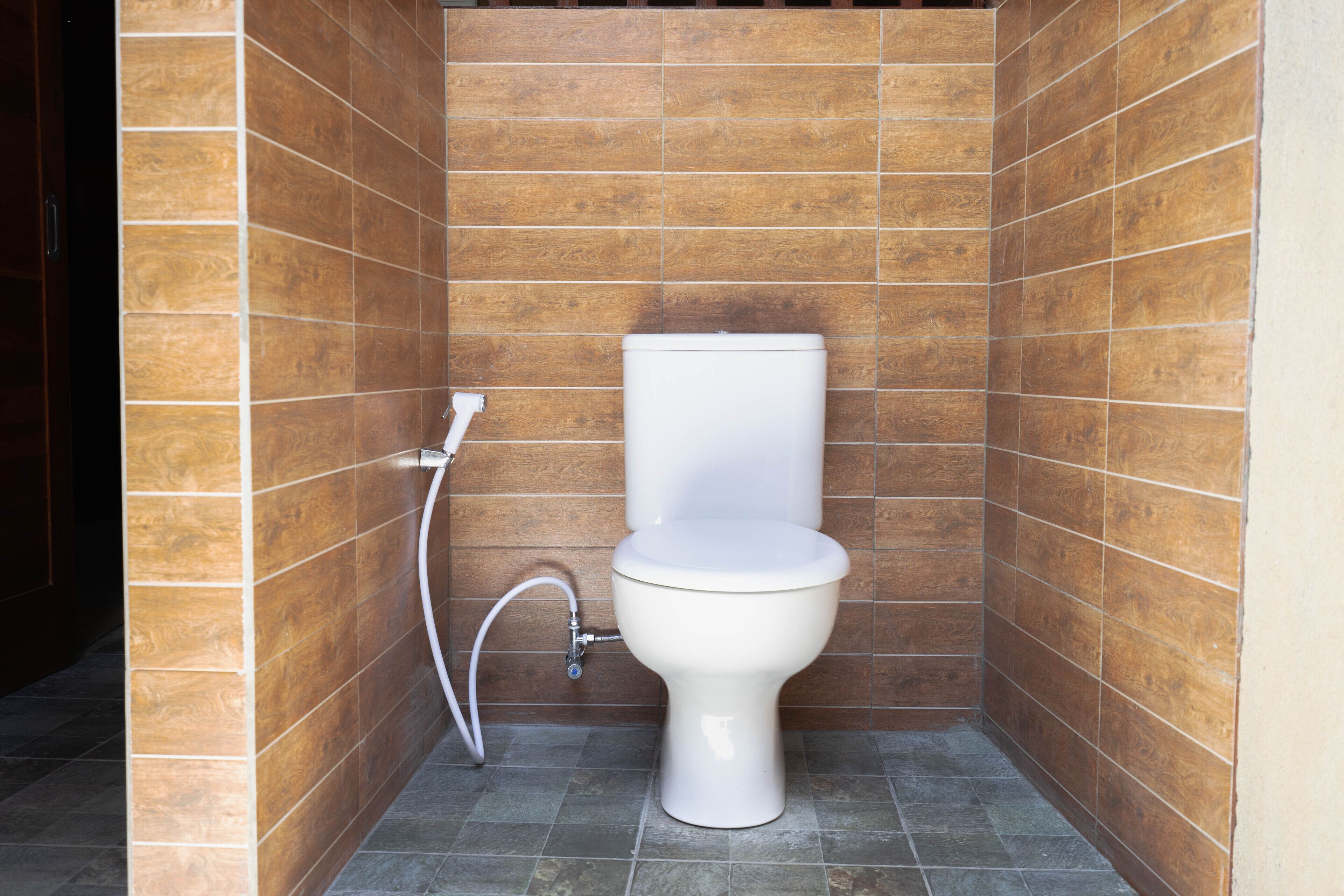 A small, modern bathroom with a white toilet, a shower, and tiled walls.