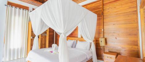Un dormitorio con estructura de madera, una cama con dosel, una mesita de noche y un buró.