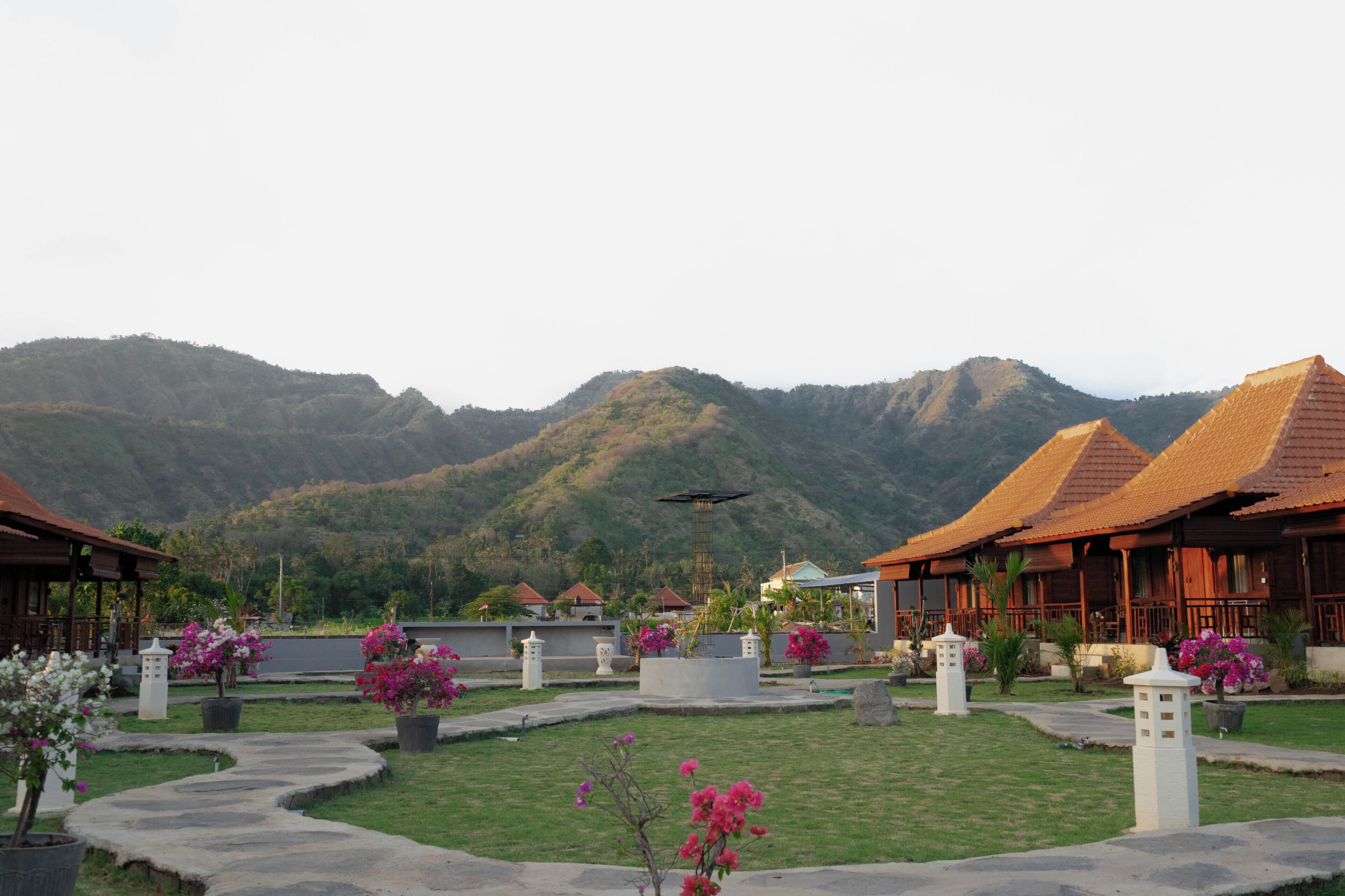 A resort with traditional architecture, a central courtyard, and a mountainous backdrop.