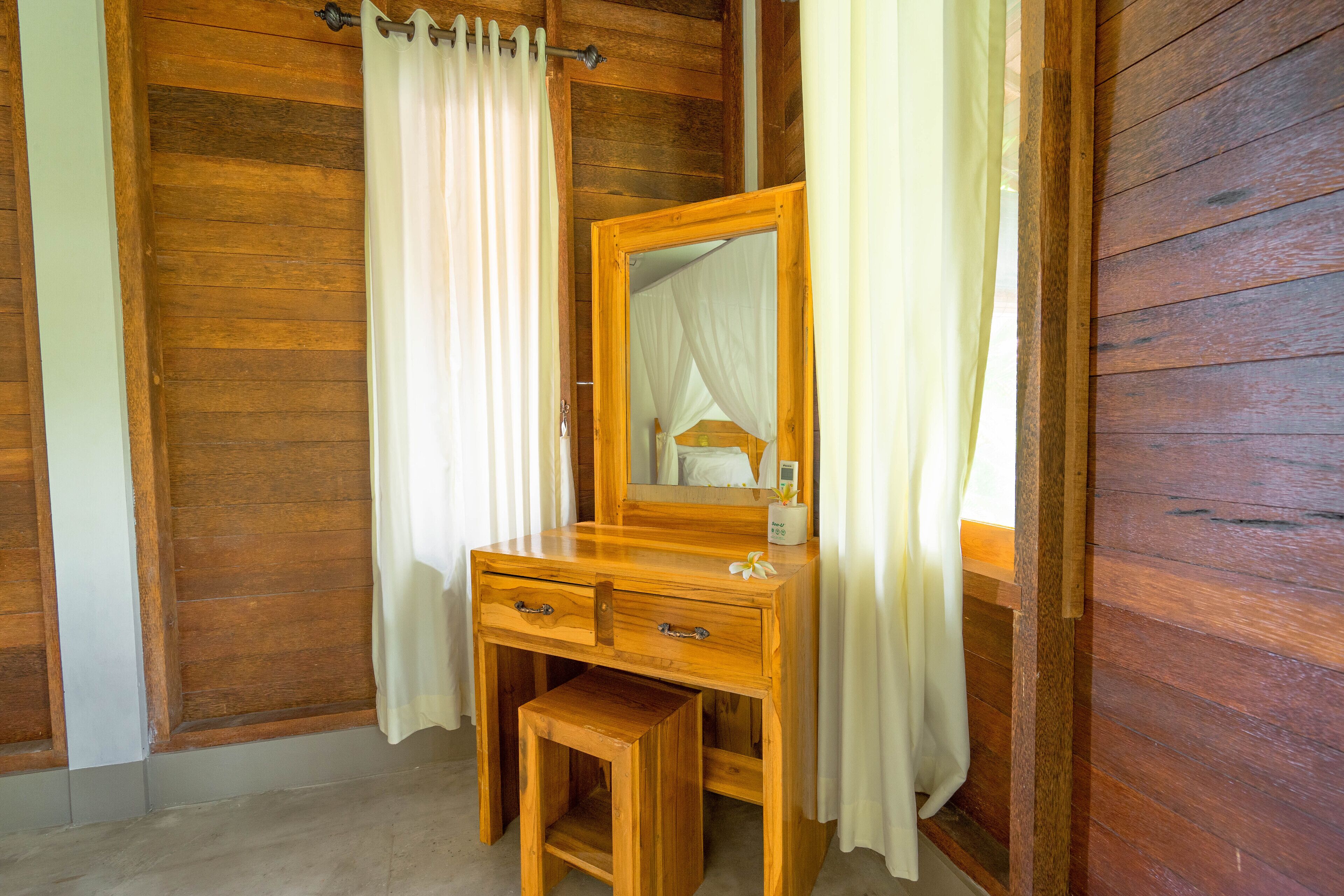 A wooden vanity with a mirror, two drawers, and a small stool.