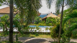 Ein tropisches Resort mit Swimmingpool, Palmen und traditioneller Architektur.