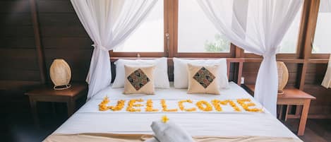 Una cama con un letrero de flores que dice 'WELCOME', una botella y toallas.