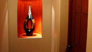 Un pasillo con una puerta de madera y una obra enmarcada en la pared.