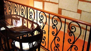 Un área de comedor con una mesa redonda y sillas, una barandilla decorativa de metal y una pared de piedra con diseño de ladrillo.