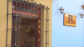 Entrada de un edificio con una reja de metal, un letrero que dice "MARHIALJA" y una pared azul.