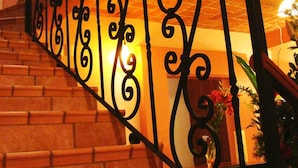 Una escalera de madera con barandillas de metal negro ornamentado y pasamanos.