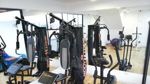 Un gimnasio con diversas máquinas de ejercicio, incluyendo una máquina de remo, una prensa de piernas y un banco de pesas.